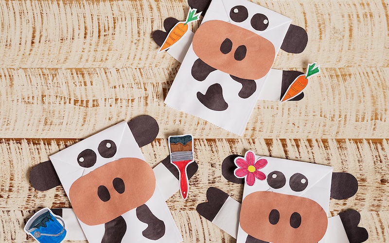 Three cow puppets laying on a table