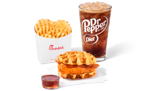Chicken & Waffles Sandwich on napkins with a side of Classic Syrup next to Waffle Fries and a Diet Dr Pepper
