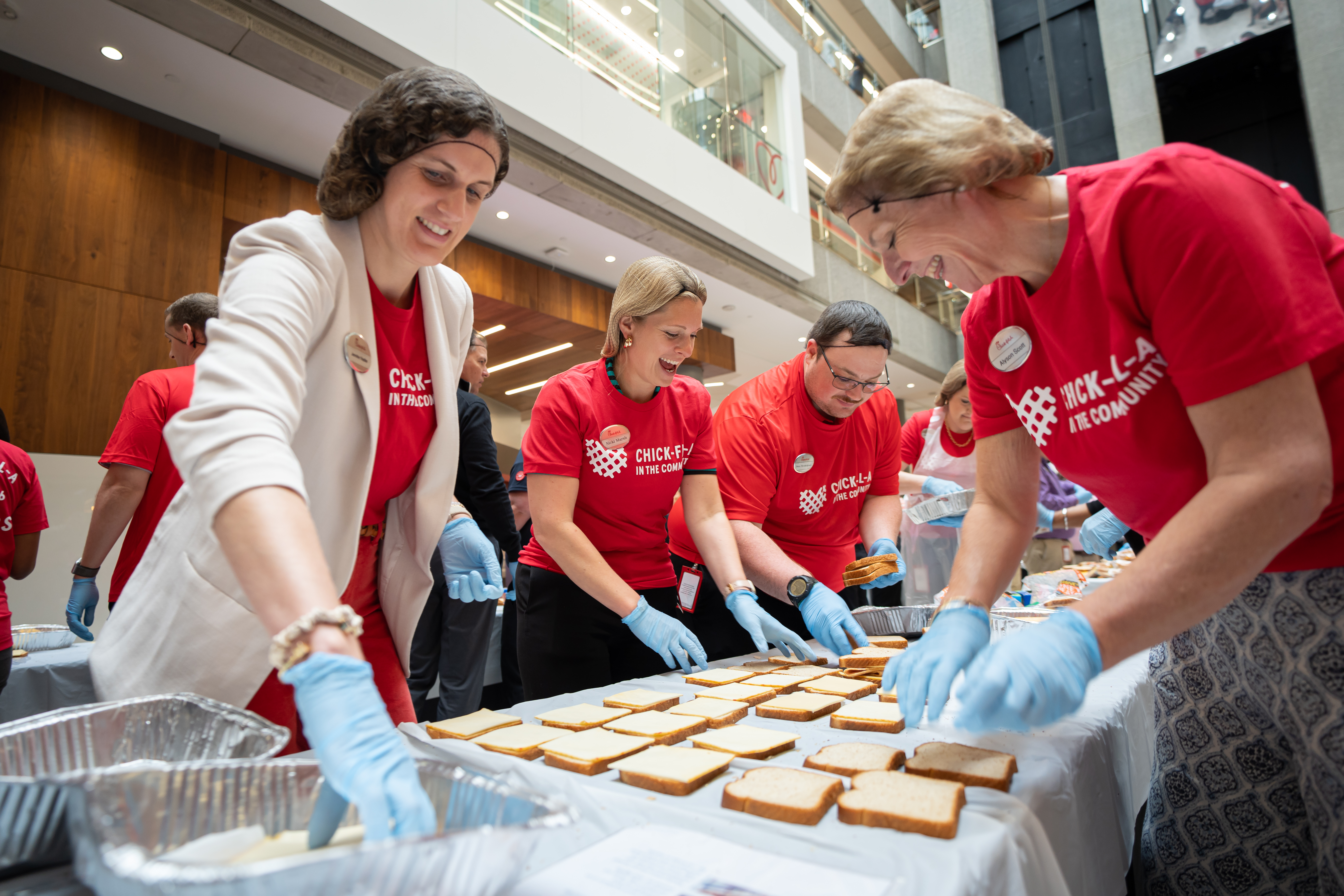 Chick-fil-A Team Members prepare meals for distribution under a Chick-fil-A tent.