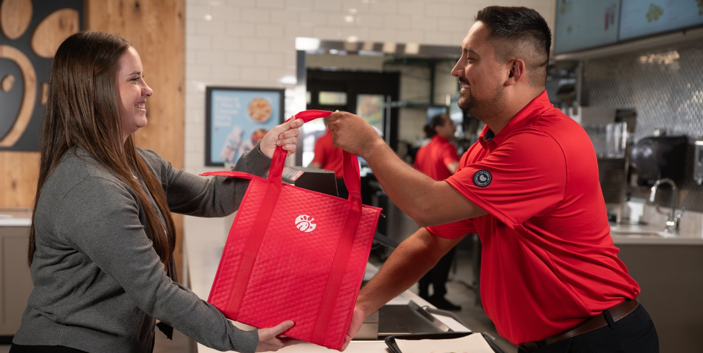 Two team members handing a bag of donated food through the Shared Table program.
