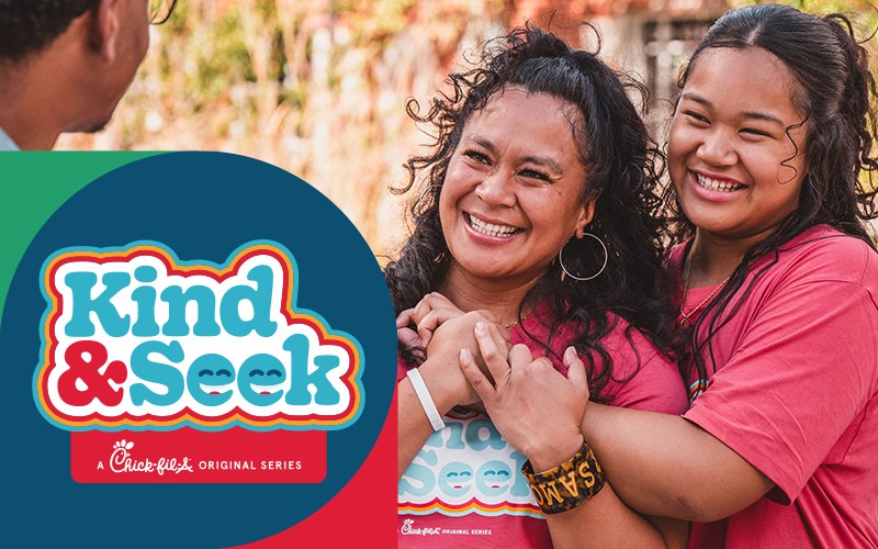 Three people standing together outside and smiling with the Kind & Seek logo overlaying the photo